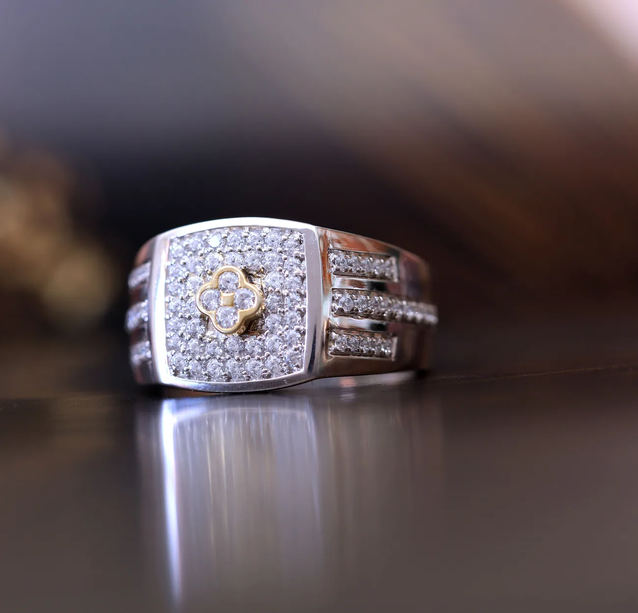 A diamond-set gold ring photographed on a dark polished surface
