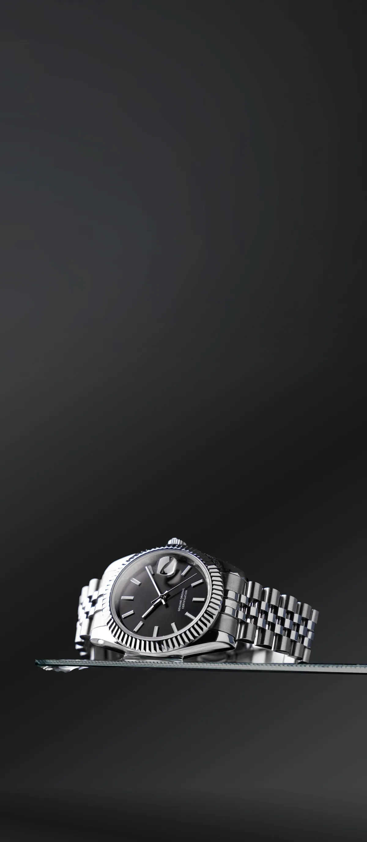 A luxury wristwatch photographed on a dark reflective surface
